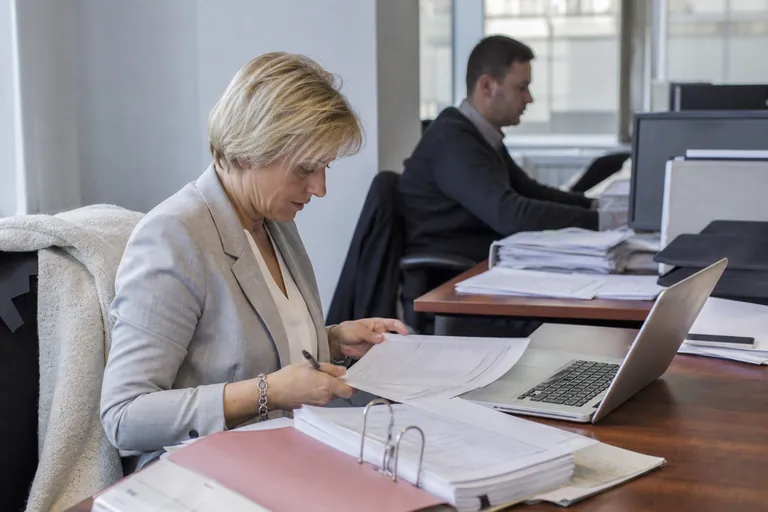 Aktenordner, Tabelle und Laptop mit Vorgangsliste auf einem Schreibtisch