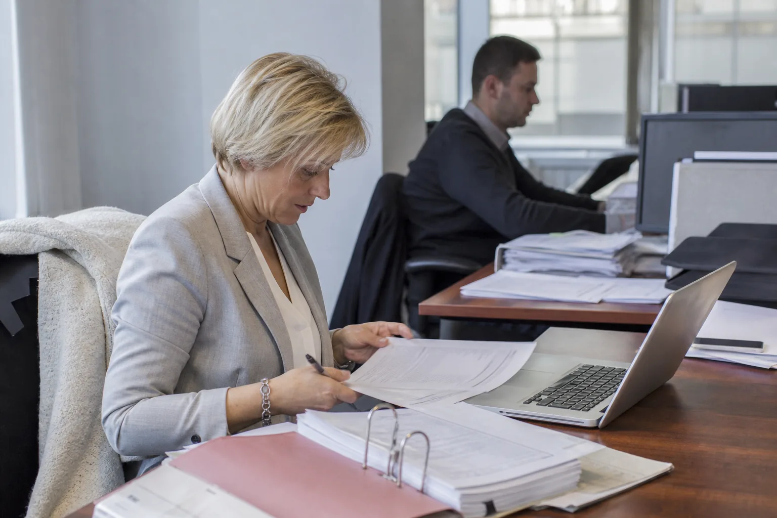 Aktenordner, Tabelle und Laptop mit Vorgangsliste auf einem Schreibtisch
